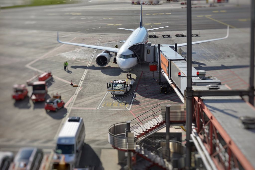 A bustling airport scene with an airplane on the tarmac being prepared for departure.